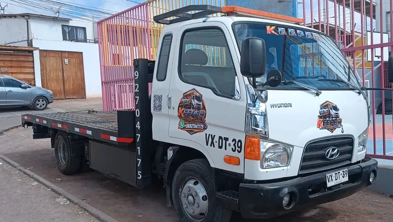 Grúa Keeper blanca con su logo y número de contacto en la puerta