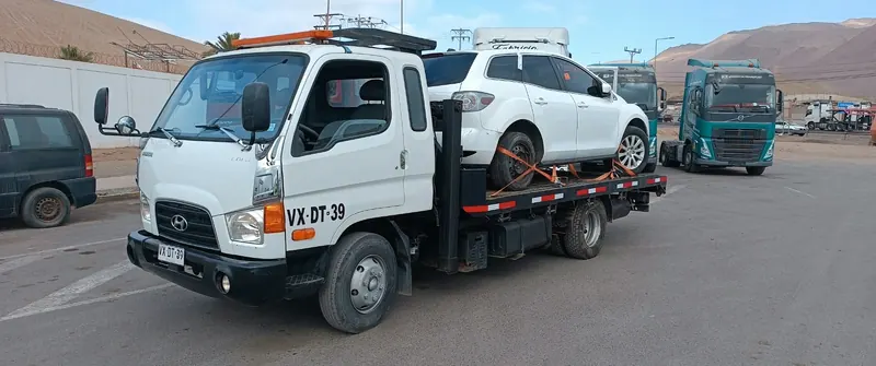 SUV blanca asegurada con eslingas naranjas sobre la plataforma de la grúa Keeper